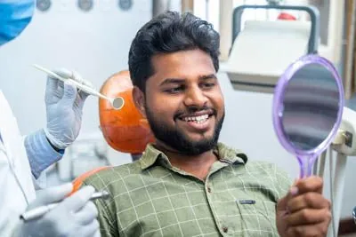 Holt Dental patient looking at his smile in the mirror after getting dental bonding