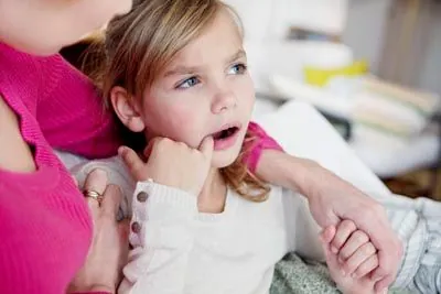 young girl holding her mouth due to tooth pain